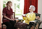 een bejaardenhelpster zit samen met oudere dame